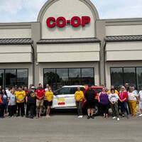 SGEU members and Co-op employees pose beside the SGEU SUV in front of the Rochdale Sherwood Co-op Food Store in Regina.