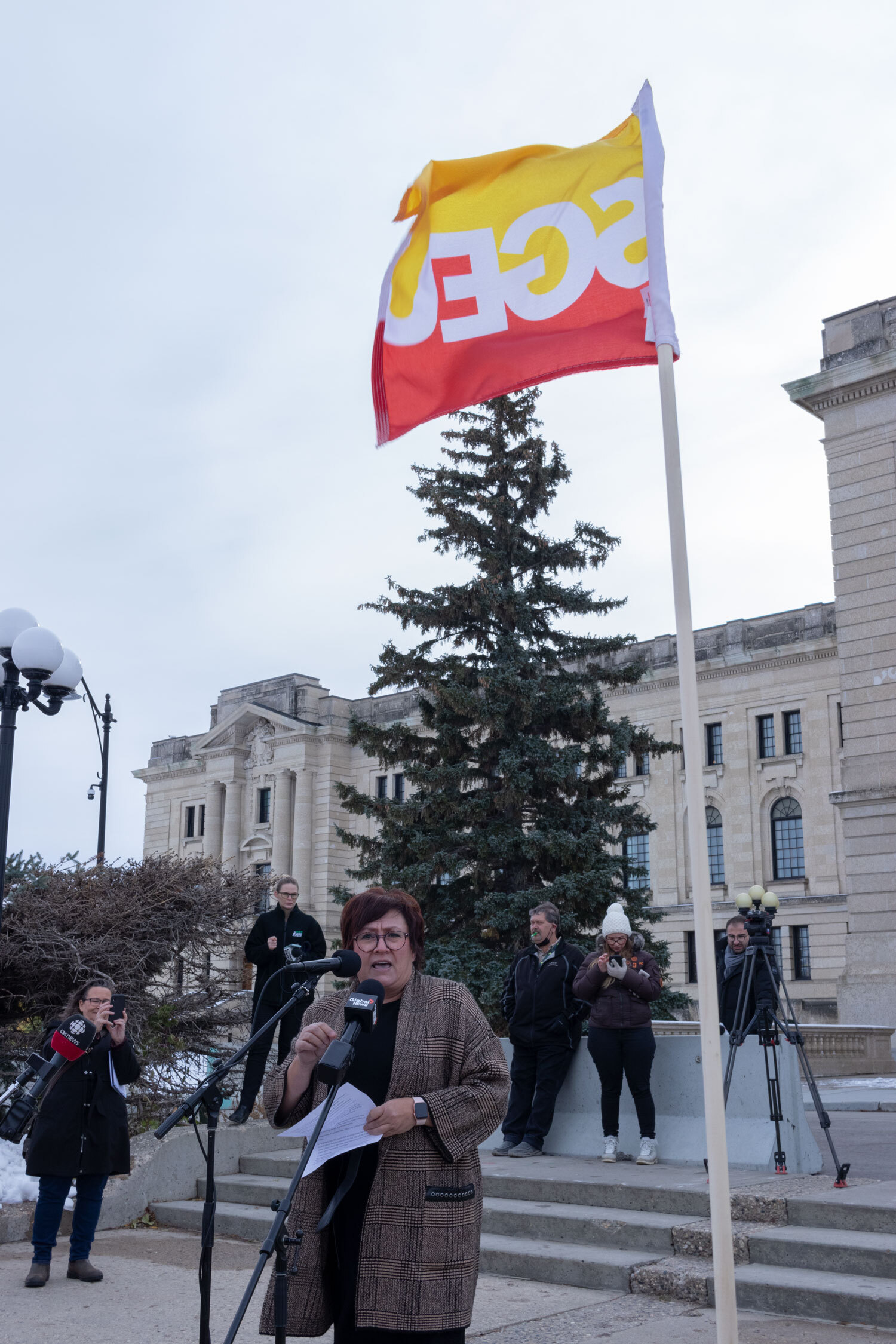 SGEU President Tracey Sauer is giving a speech in front of the Legislative Building.